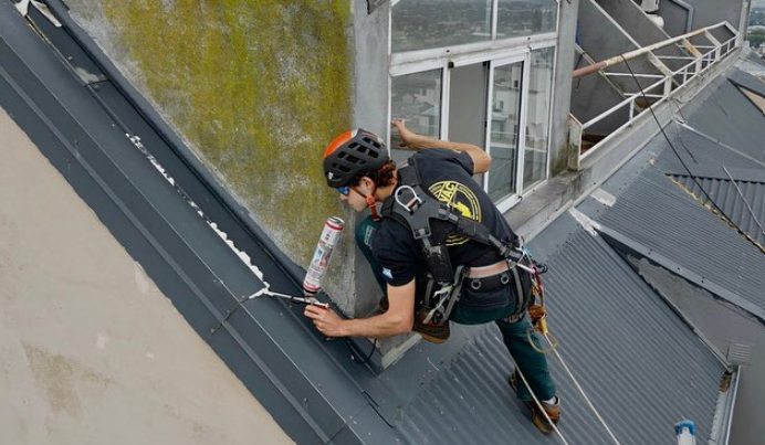 Técnico con equipo de seguridad trabajando en el techo de un edificio